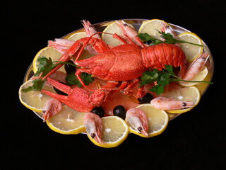 Boiled shrimp and crayfish on a plate surrounded by lemon wedges.