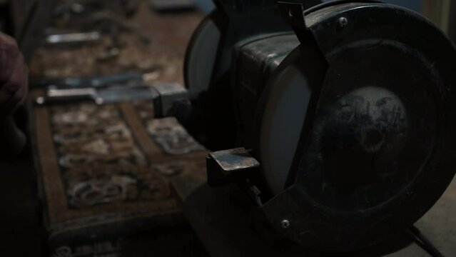 Sharpening an ax on an electric grinding wheel, Machine sharpening an ax on an electric grinder, hand sharpening on a rotating grinding stone, close-up.