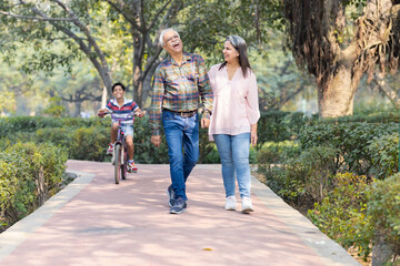 Obraz premium Happy grandparents spending leisure time with grandson at park