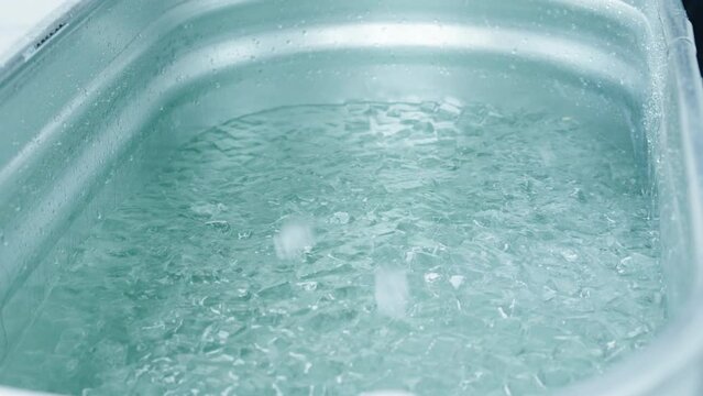 Filling The Steel Bathtub With Ice Cubes For The Wim Hof Ice Bath Experience. - Low-Angle Shot