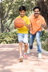 Obraz premium Father and son playing basketball at park.