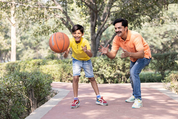 Father and son playing basketball at park.