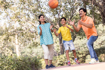 Cheerful family having fun playing with basketball at park.