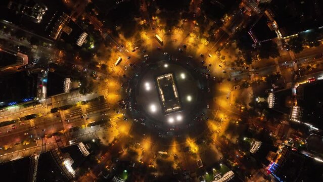 Drone rotates from above, around the Arc de Triomphe, topshot, many cars drive in circles around the Arc de Triomphe in Paris