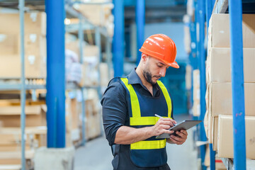 Warehouse workers in helmets checking goods and supplies on shelves with goods background in warehouse worker packing in a large warehouse in a large warehouse. Logistics industry concept.