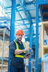 Warehouse workers in helmets checking goods and supplies on shelves with goods background in warehouse worker packing in a large warehouse in a large warehouse. Logistics industry concept.