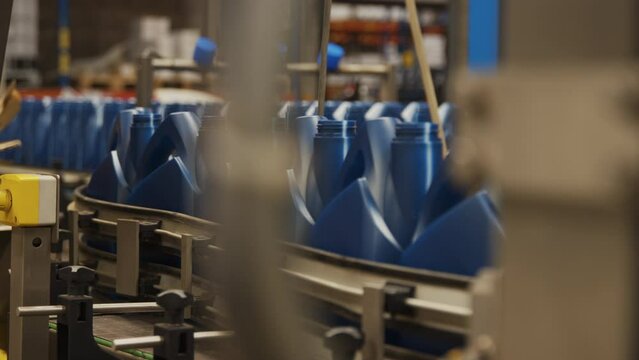 A factory line moving blue oil jugs