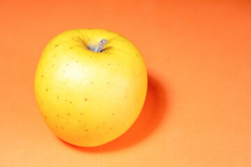 Fresh ripe juicy yellow apple fruit on orange background