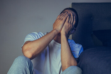 Depressed man sitting on the floor with his head down and leaning against the wall. In frustrated...