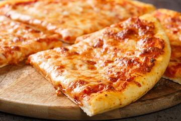 Delicious crispy New York style pizza with melted cheese and base tomato sauce close-up on a wooden board on the table. Horizontal