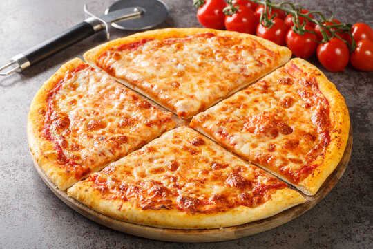 Homemade New York style pizza with mozzarella cheese and spicy tomato sauce close-up on a wooden board on the table. Horizontal