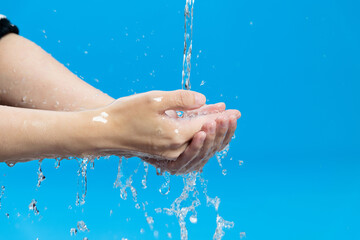 Washing hands with water on blue background