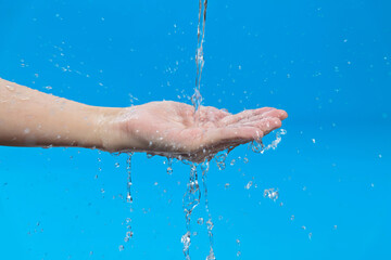 Woman hand catching water on blue background