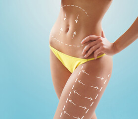 Beautiful woman with slim and sporty body in swimwear having arrows along her stomach and legs. Fat...