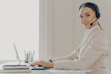 Smiling call center agent in headset consulting client