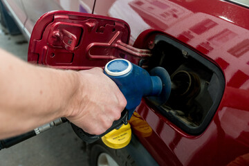 A man hand holding pump filling gasoline. Pumping petrol into the tank. A car refuel on gas station