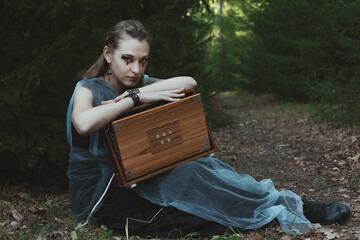 Celtic inspired fantasy scenic photography. Picture of witch with wooden box and deep dark forest...