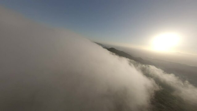 FPV drone soaring above clouds across Alella, Catalonia woodland wilderness below
