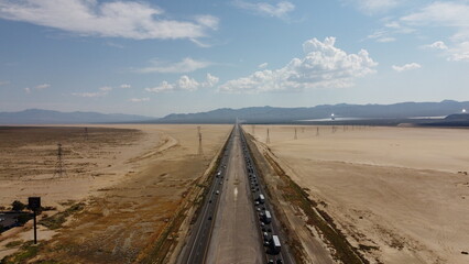 Fototapeta premium Aerial drone shot of state border between Nevada and California highway 15 facing South West during rush hour traffic on a clear sunny day with a cloudy sky overlooking Mojave National Preserve 