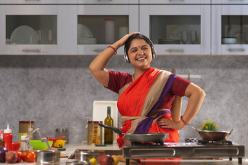 Woman with headphones dancing in the kitchen while cooking