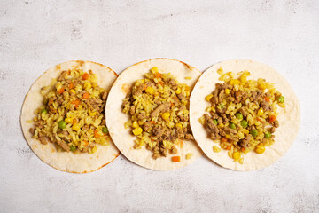 Three tortilla tortillas stuffed with rice, meat, corn for making tacos and burritos.