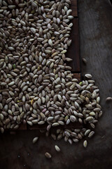 Pistachio nut in sack bag with mint green leaf on wooden table background.