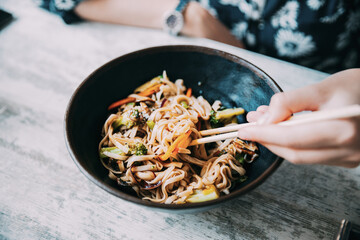 Woman eating asian noodles udon with pork in cafe. Asian noodles udon with pork close-up in a bowl...