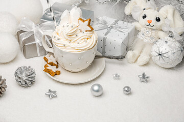 Christmas cup of whipped cream on table with soft toy rabbit, christmas tree and other home...
