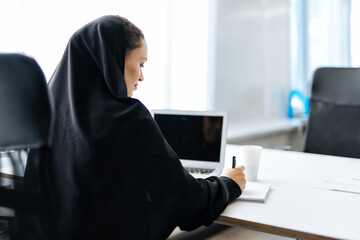beautiful woman with abaya dress working and printing documents. Middle aged female employee at...