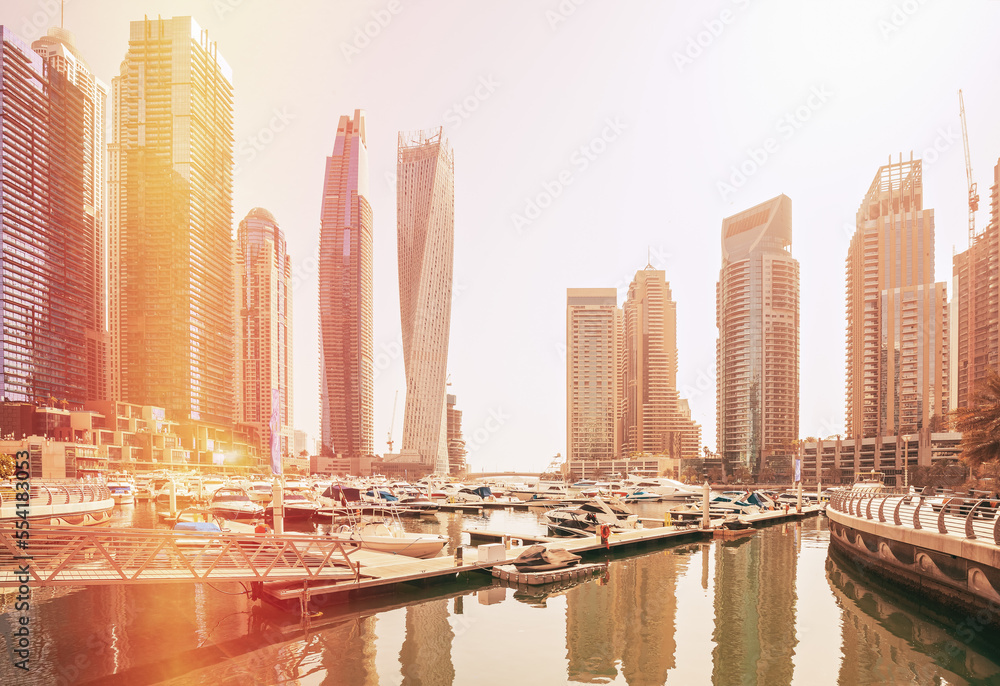 Wall mural View of high-rise buildings of residential district in Dubai Marina and yachts moored near pier in sunny day. Dubai Marina Towers. Flare sun, film effect, lens flare, glow, film light, flare