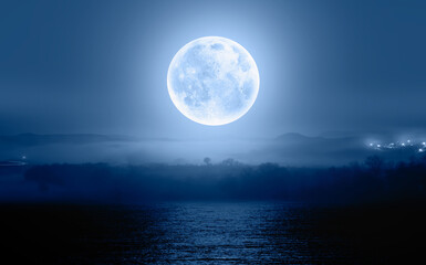 Night sky with blue moon in the clouds over the calm blue sea "Elements of this image furnished by NASA