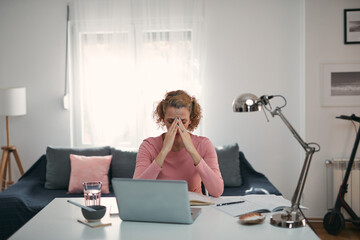 Woman with eyes hurting, sinus problem, headache, head pain, working from home troubles and issues.