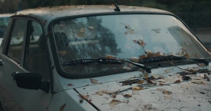 Very old and dirty car front with leafs in late autumn slow motion 4K