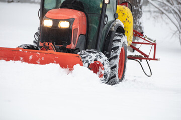 Tractor cleaning urban park paths on a cold snowy day.