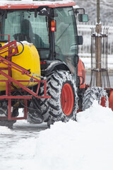 Tractor cleaning urban park paths on a cold snowy day.