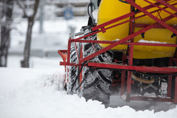 Tractor cleaning urban park paths on a cold snowy day.