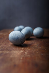 Blue diy painted easter eggs on brown wooden rustic table, grey background. Vertical shot, copy space