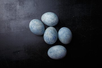 Easter eggs painted blue on black wooden background. Top view, copy space