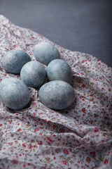 Easter eggs DIY painted blue on grey wooden background with kitchen towel. Copy space, vertical shot
