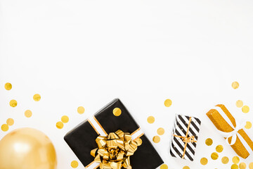 Christmas flat lay. Christmas gifts, black and golden wrapping paper on white background with golden confetti