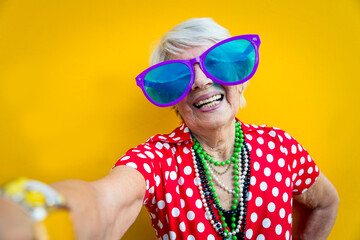 Happy and funny  grandmother posing on colored backgrounds. Old woman having fun and celebrating. Concept about third age and seniority