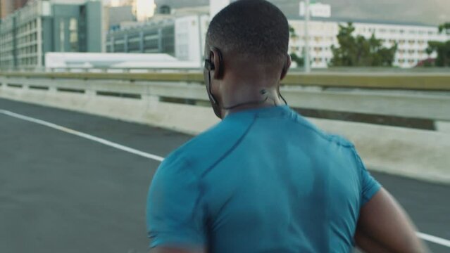 City, fitness or black man running on road in cardio training, workout or exercise to prepare for a fast sprinting race. Sprinter, back view or healthy athlete runner exercising with speed or focus