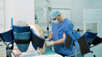 Doctor prepares patient for surgery. Creative. Patient sits while doctor prepares patient for surgery in operating room. Preparation and injection of anesthesia to patient in operating room