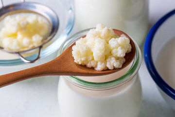 Kefir fermented milk drink with kefir grains. Homemade kefir stands in a glass, next to kefir grains and milk