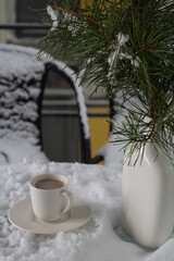 Obraz na płótnie Canvas photo cup and saucer standing on the snow next to a vase with fir branches