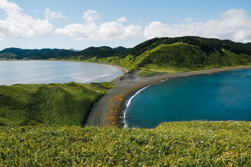 View of a small spit and two bays against the backdrop of mountains.