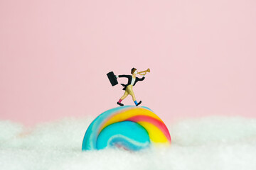 Miniature people toy figure photography. Playground island above clouds. A clown wearing black suit...