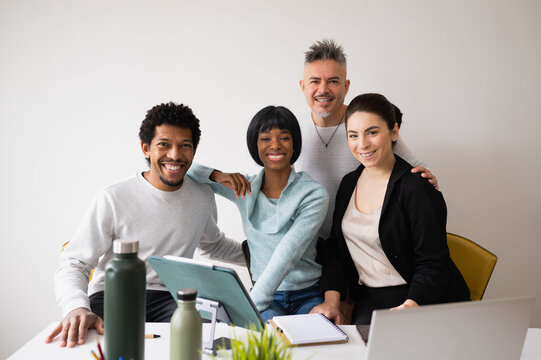 Portrait with group of five mixed race teamwork in office. People smiling looking at camera.
