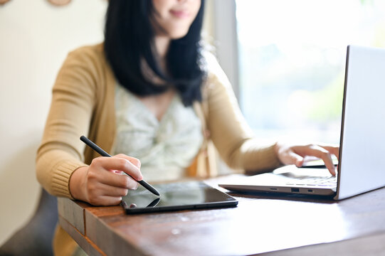 cropped image, An Asian female remote working at the coffee shop using laptop and tablet.