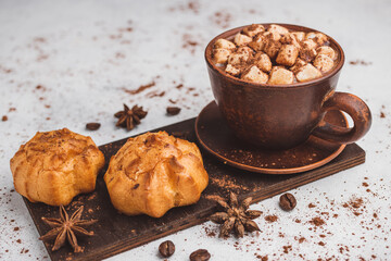 Hot chocolate drink with marshmallows in a cup and sweet bakery eclair dessert sprinkled with cocoa...